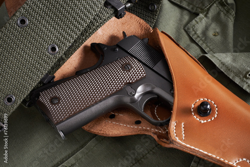 Colt pistol in holster and belt lie on military jacket