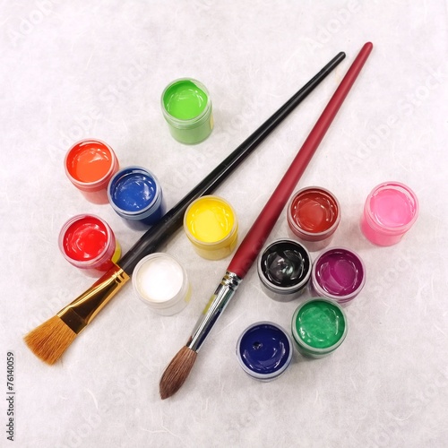 Paint set and brushes on white textured paper background