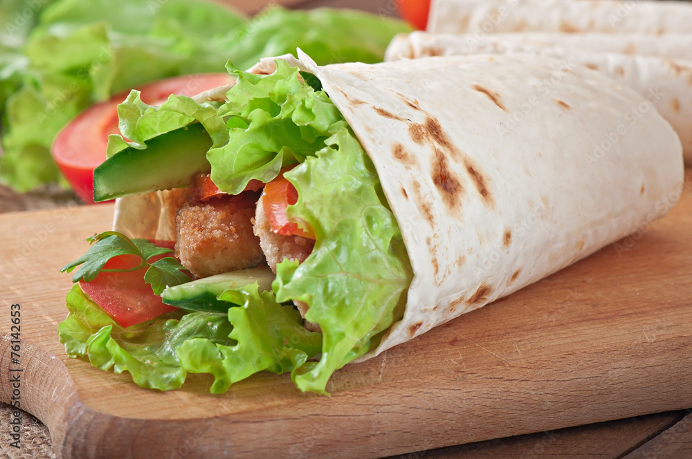 Obraz premium Fresh tortilla wraps with chicken nuggets and vegetables on plat