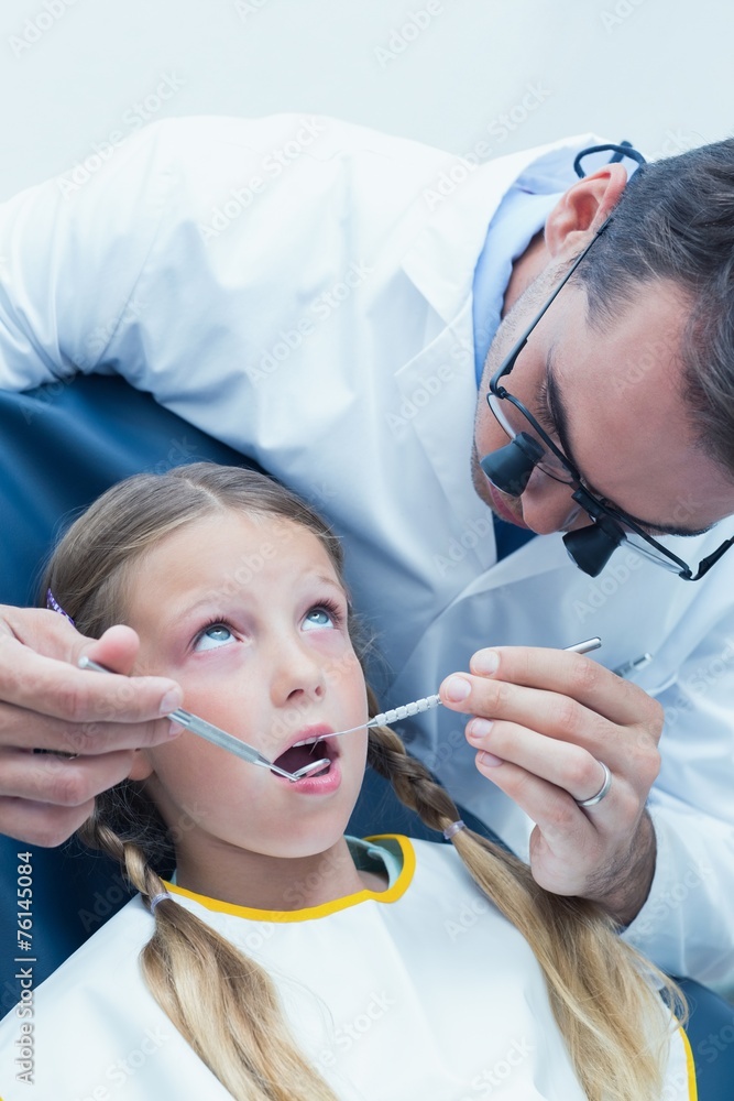 Male dentist examining girls teeth Male dentist examining girls teeth