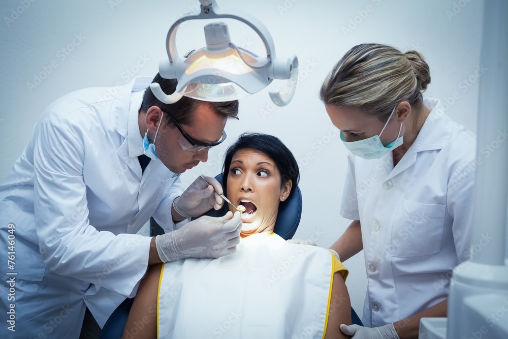 Fototapeta premium Dentist with assistant examining womans teeth