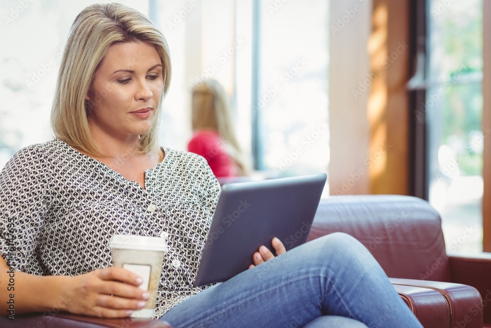 Woman using digital tablet and holding disposable cup Woman using digital tablet and holding disposable cup