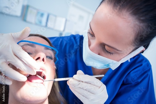 Dentist examining a patients teeth in the dentists chair