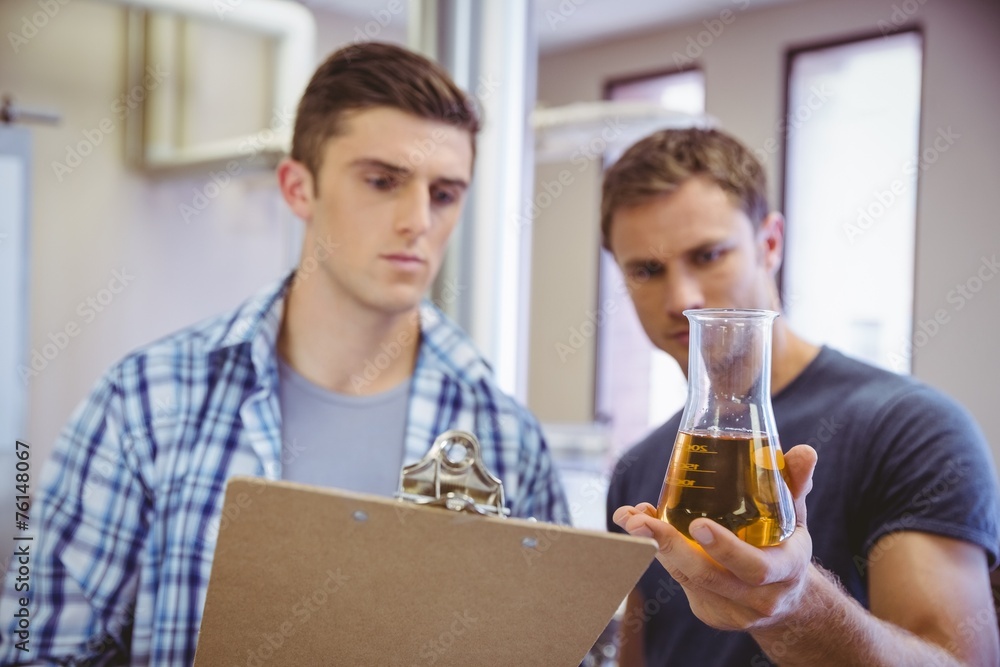 Two men looking at the beaker with beer Two men looking at the beaker with beer