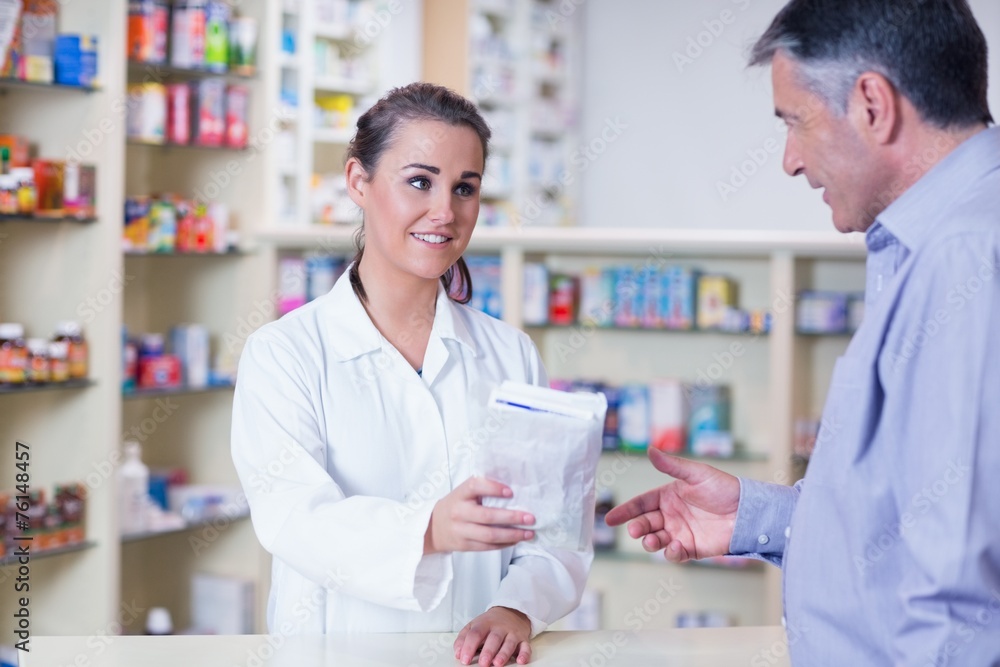 Trainee giving a bag of pills to a customer