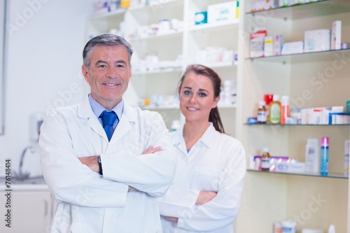 Pharmacist with his trainee standing with arms crossed