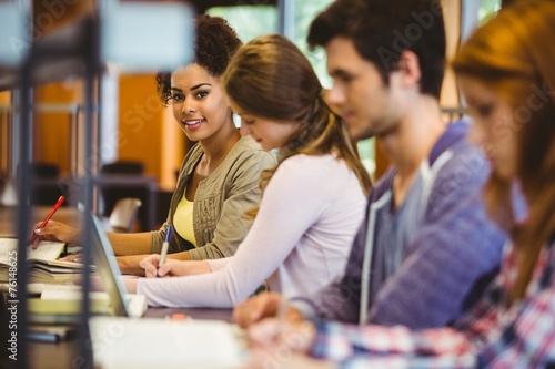 Student looking at camera while studying with classmates