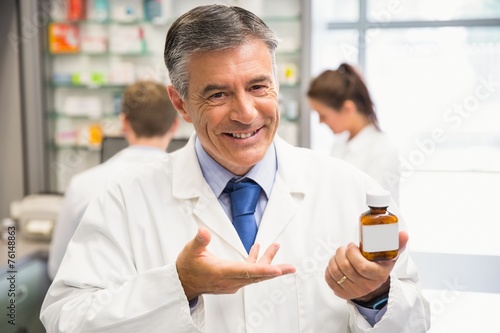 Senior pharmacist showing medicine jar