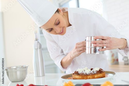 Pastry cook spreading icing sugar on tart