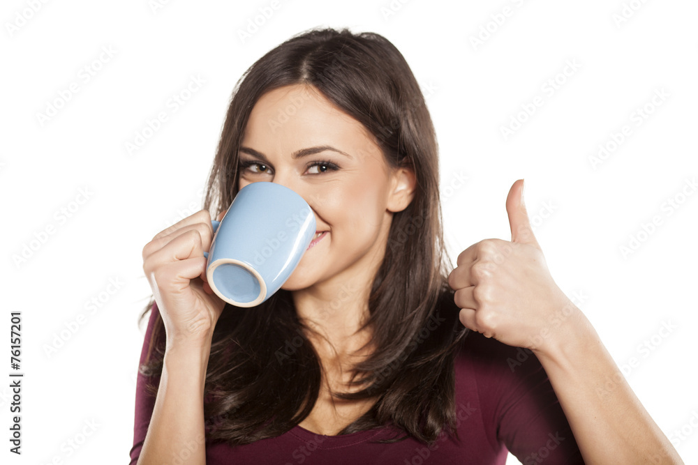 happy young woman drinking tea and showing thumbs up happy young woman drinking tea and showing thumbs up