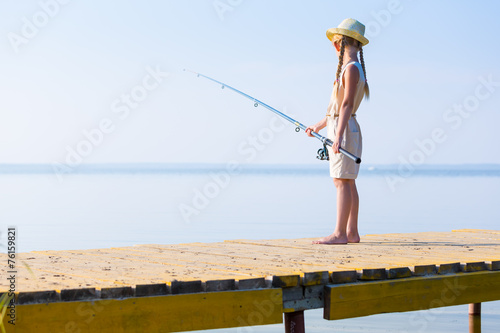 Girl in a dress and a hat with a fishing rod