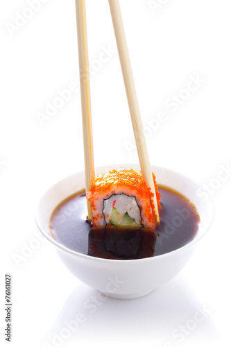 Sushi in chopsticks dipped in soy sauce isolated 
