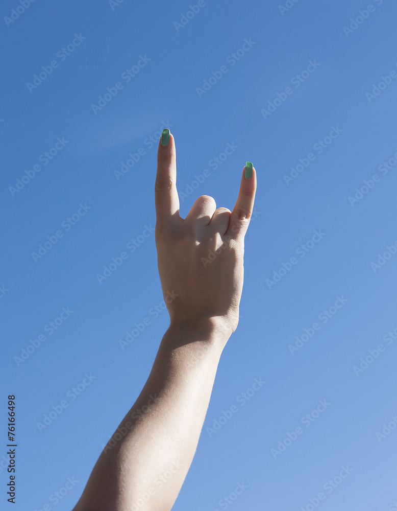 Female hand up in the sky making sign of the horns Female hand up in the sky making sign of the horns