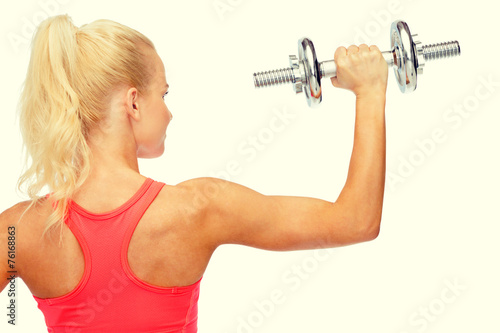 sporty woman with heavy steel dumbbell from back