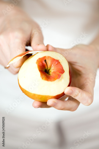Woman’s hands pare red apple