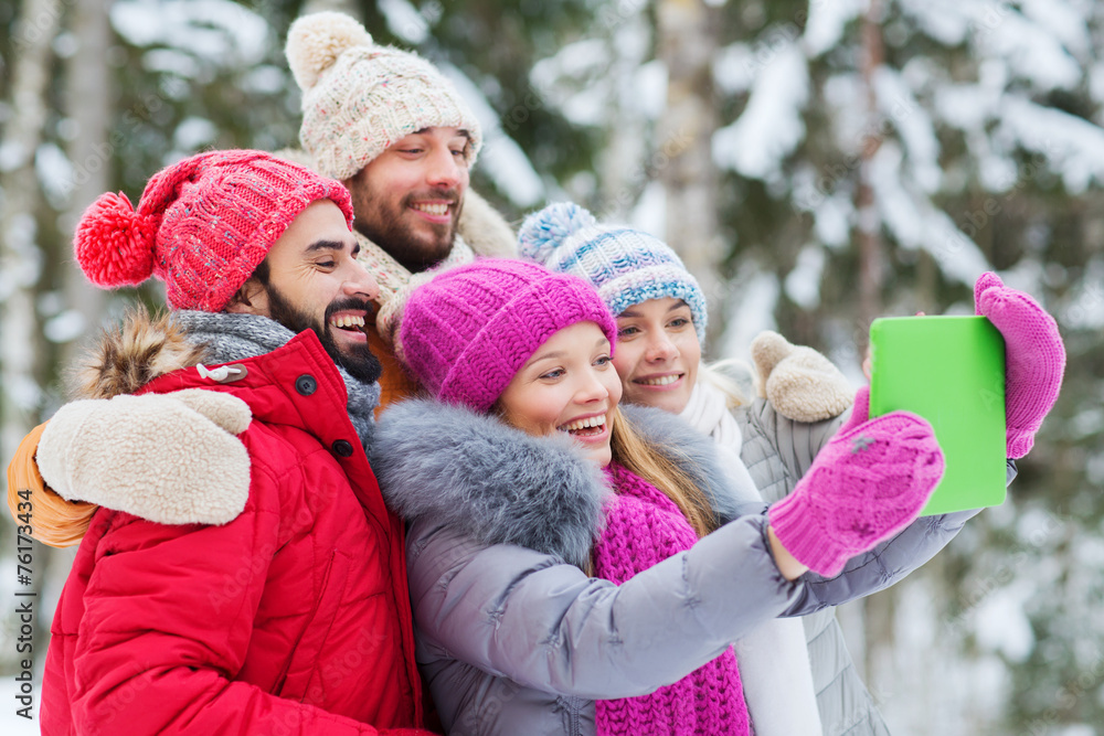 smiling friends with tablet pc in winter forest