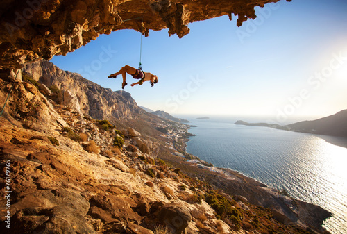 Female rock climber hanging on rope while lead climbing