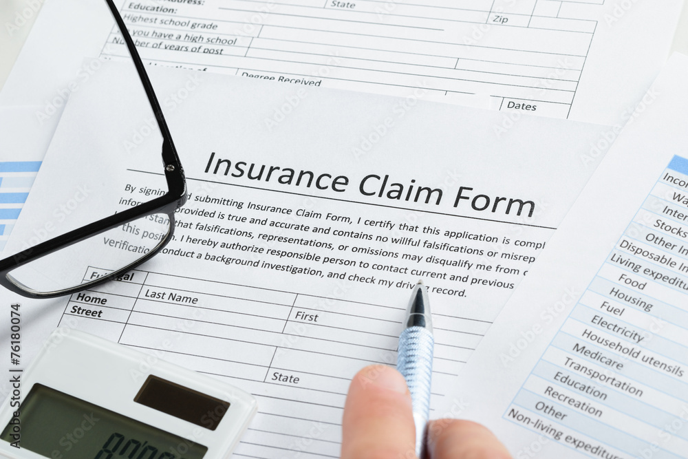 Hand With Pen On Insurance Claim Form Hand With Pen On Insurance Claim Form