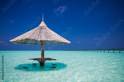 Fototapeta Naklejka Na Ścianę i Meble -  Bamboo beach umbrella with bar seats in the water