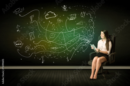 Businesswoman sitting in chair holding tablet with media icons