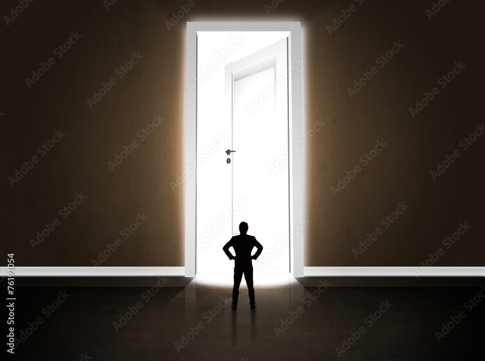 Business man looking at big bright opened door Business man looking at big bright opened door
