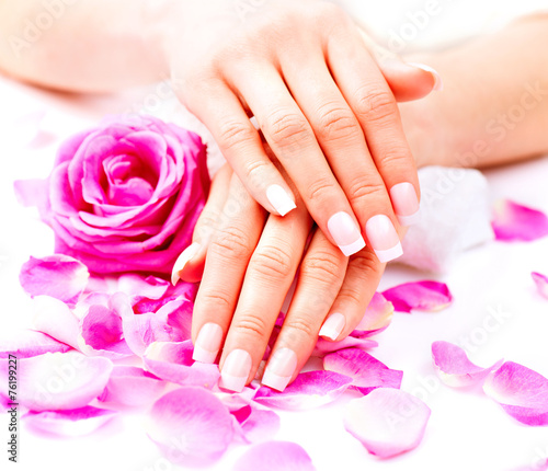 Hands spa. Beautiful female hands with pink rose flowers petals