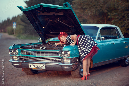Retro girl repairing blue Cadillac