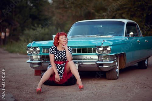 Foto Retro girl sitting near blue Cadillac