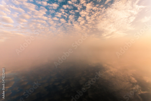 misty morning on the river and clouds reflected in water