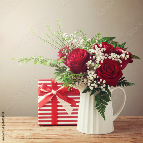 Rose flower bouquet and gift box on wooden table photo