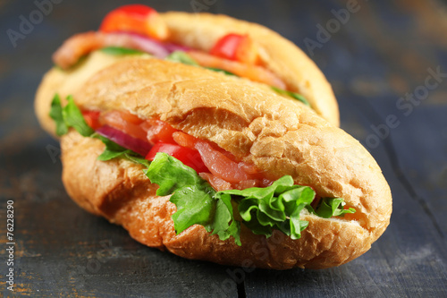 Sandwiches with salmon and vegetables on wooden background