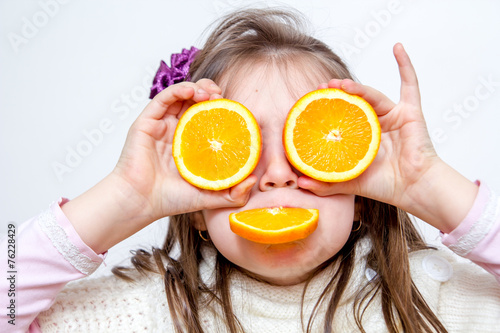 Little girl playing with orange fruits