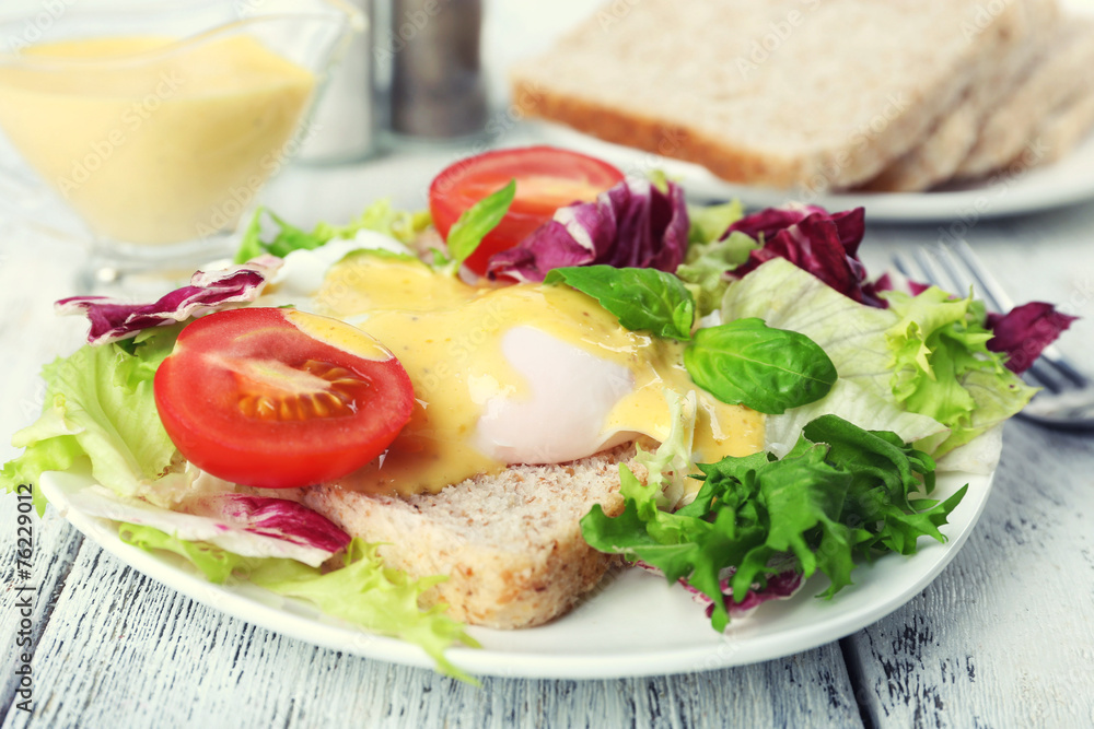 Toast with egg Benedict and tomato on plate on wooden table Toast with egg Benedict and tomato on plate on wooden table