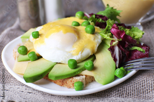 Toast with egg Benedict and avocado on plate on table close up