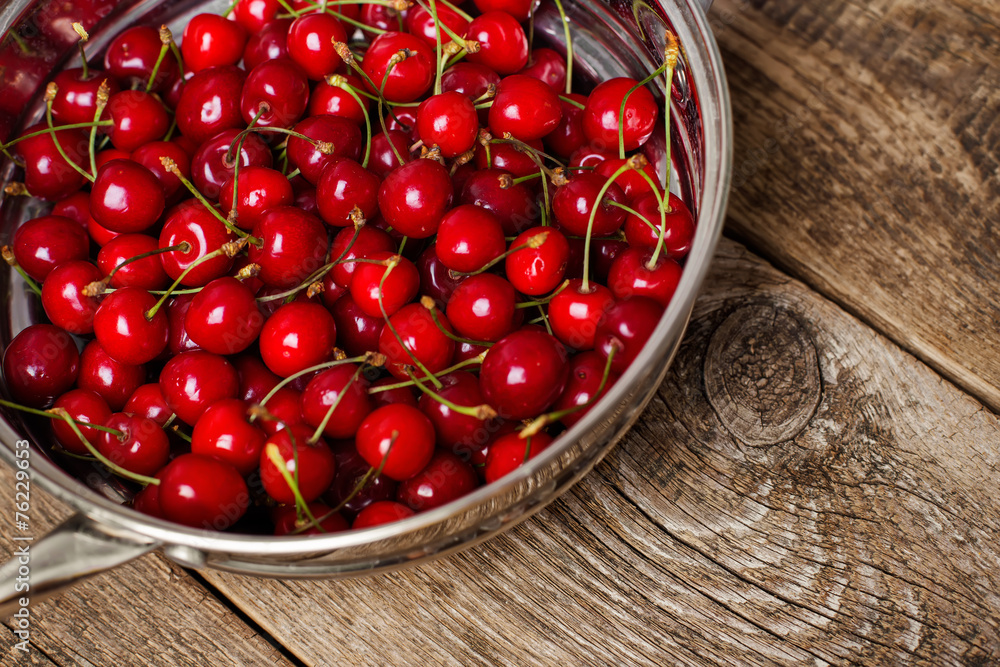 Sweet cherries in colander on color wooden background Sweet cherries in colander on color wooden background