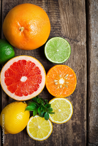 Halves of fresh citrus fruits on wooden background. Orange, grap