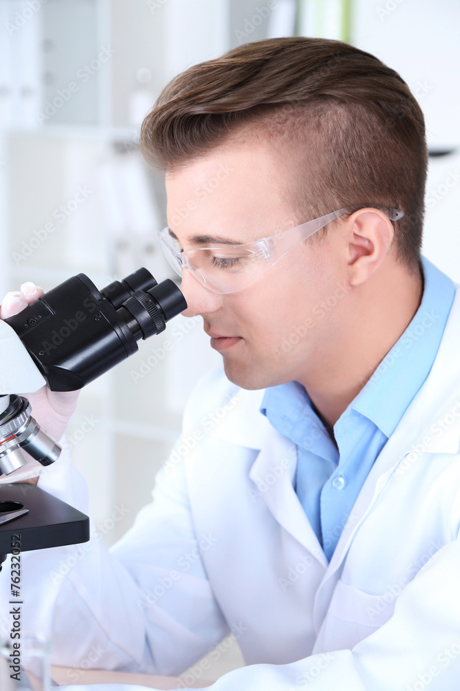Male scientist using microscope in laboratory Male scientist using microscope in laboratory