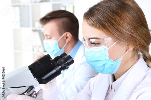 Young female and male scientists with microscope in laboratory