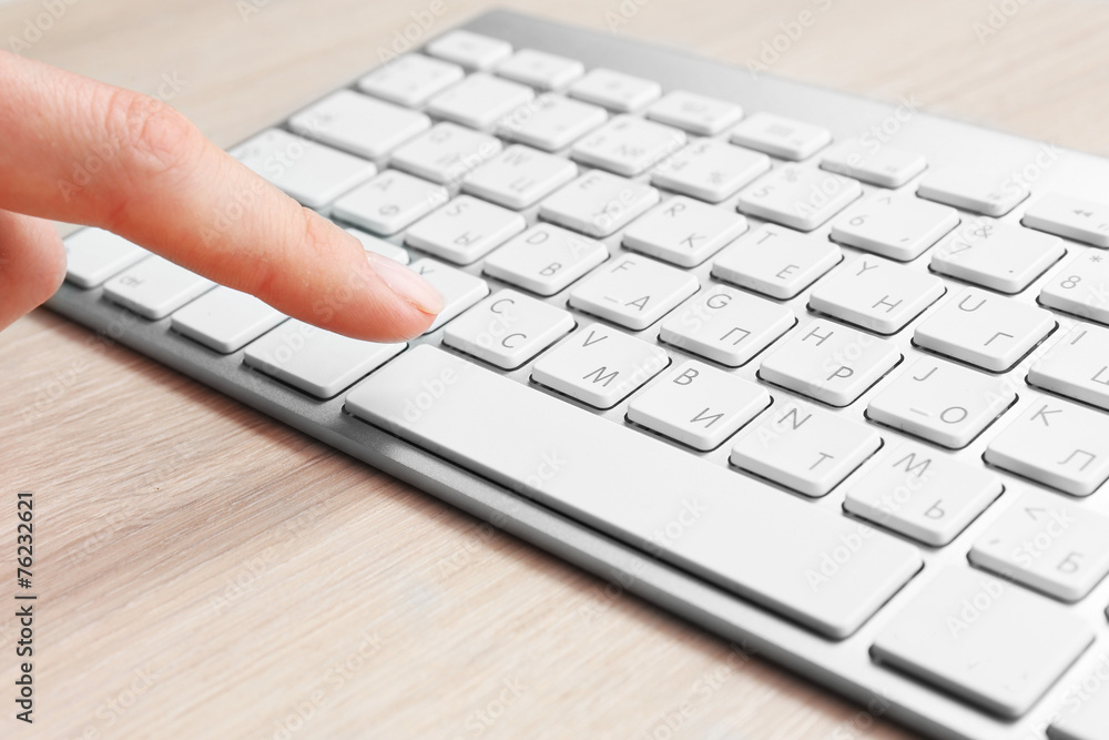 Female hand with keyboard on wooden desktop background Female hand with keyboard on wooden desktop background