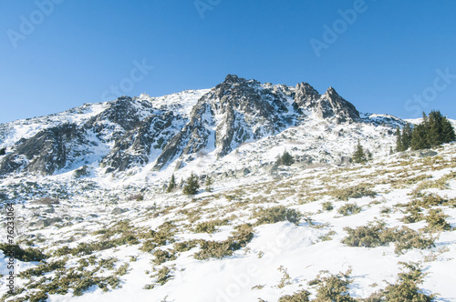 Snowy mountain rock ridge in clear sunny winter day