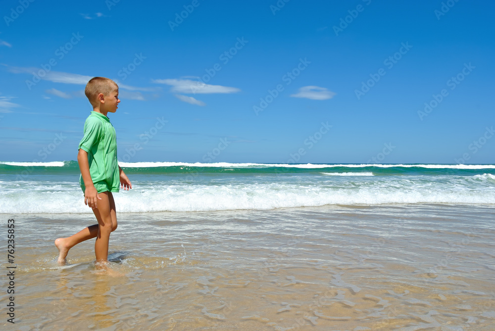 Young boy walking along the waters edge