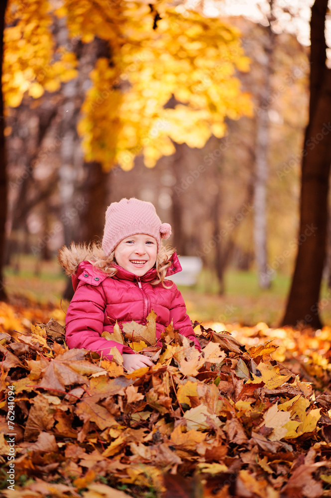 adorable child girl sitting in leaves in autumn park adorable child girl sitting in leaves in autumn park
