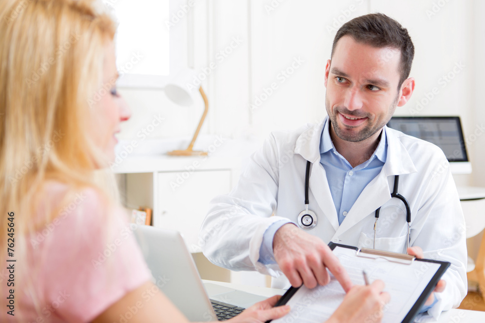 Patient signing the document of a young attractive doctor