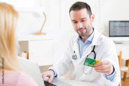 Young attractive doctor taking health insurance card
