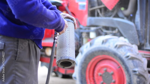 Farmer is cleaning pushcart engine air filter by air pump