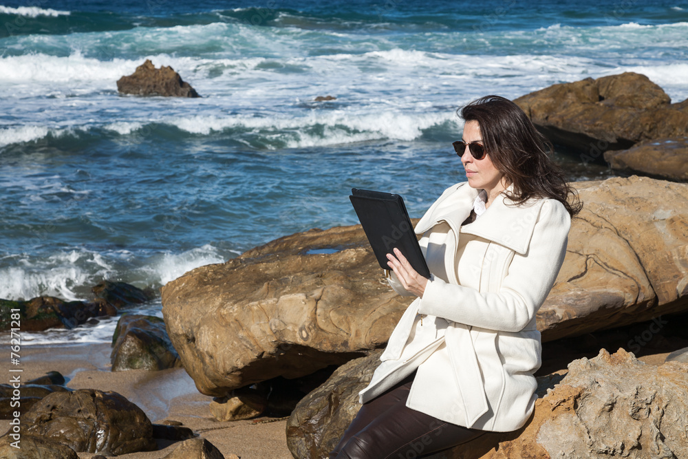 Attractive woman posing at the seaside with tablet