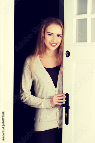 Beautiful caucasian woman standing by the door.