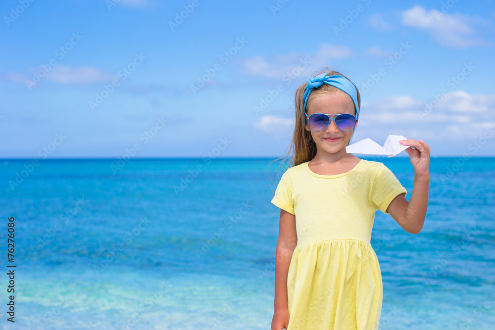 Happy little girl with paper airplane on white sandy beach Happy little girl with paper airplane on white sandy beach