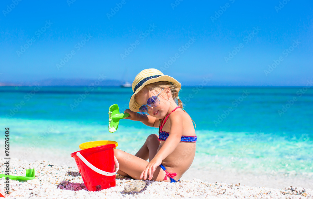 Adorable little girl playing with beach toys during tropical Adorable little girl playing with beach toys during tropical