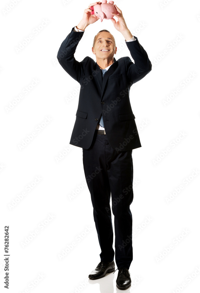 Full length cheerful businessman holding piggybank Full length cheerful businessman holding piggybank
